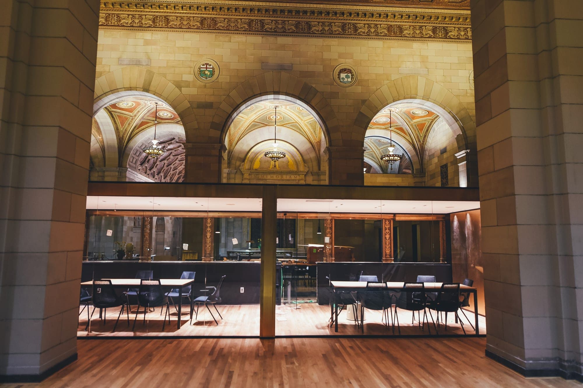 A glazed meeting room set inside the stone arches of an older building